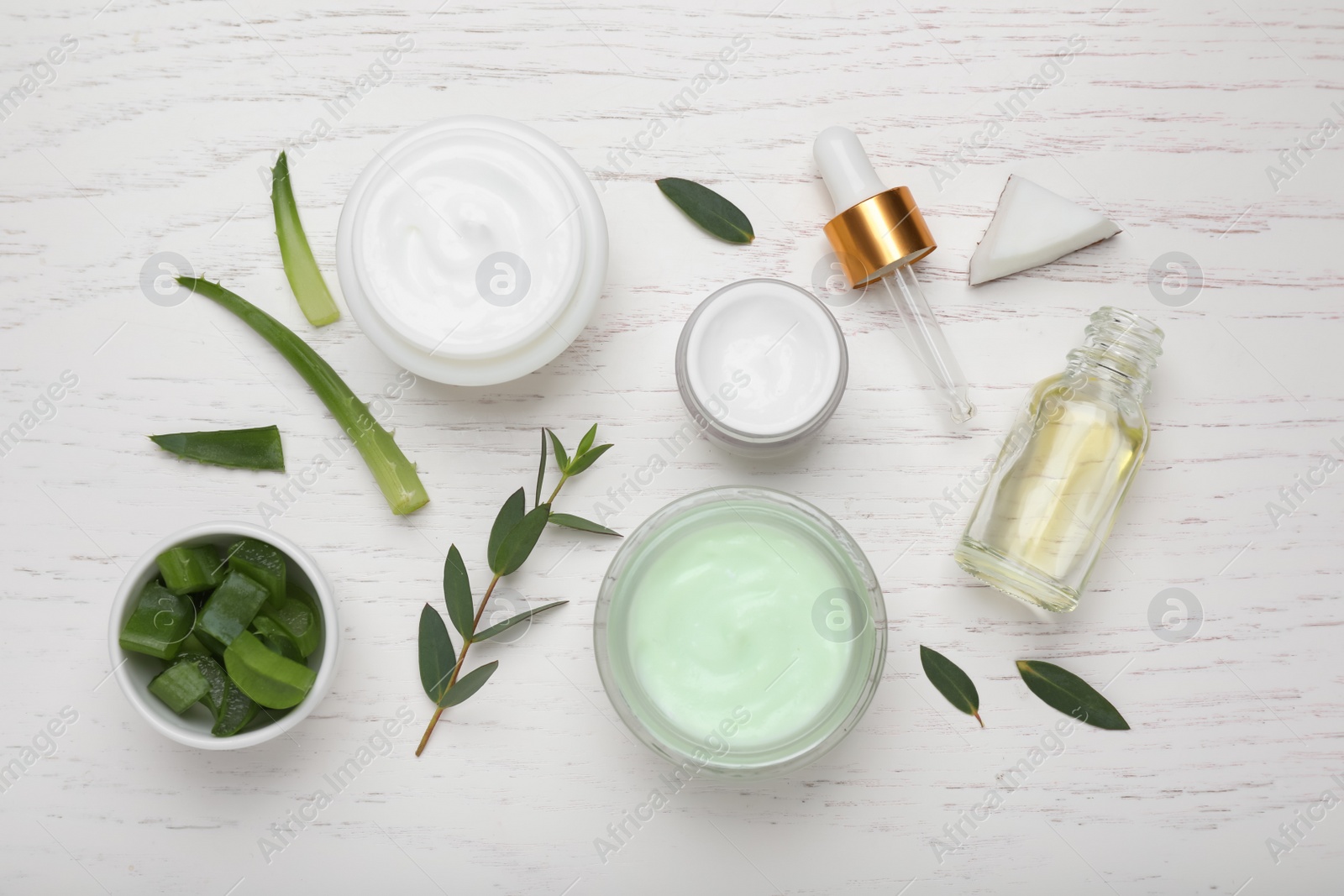 Photo of Body cream and cosmetic products, eucalyptus with aloe on white wooden table, flat lay