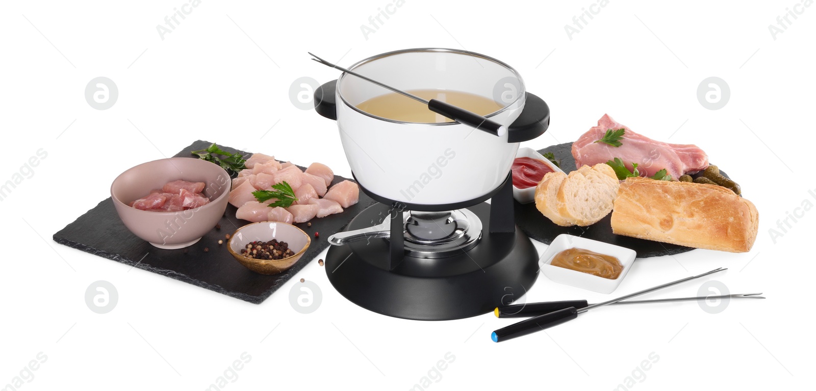 Photo of Oil in fondue pot, forks, sauces, pieces of raw meat and other products isolated on white