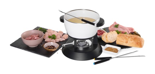 Oil in fondue pot, forks, sauces, pieces of raw meat and other products isolated on white