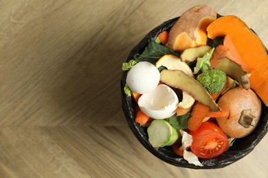 Photo of Natural garbage in trash bin on wooden background, top view with space for text. Composting of organic waste