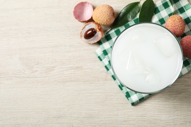 Fresh lychee juice and fruits on white wooden table, flat lay. Space for text