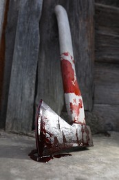 Axe with blood on floor indoors, closeup