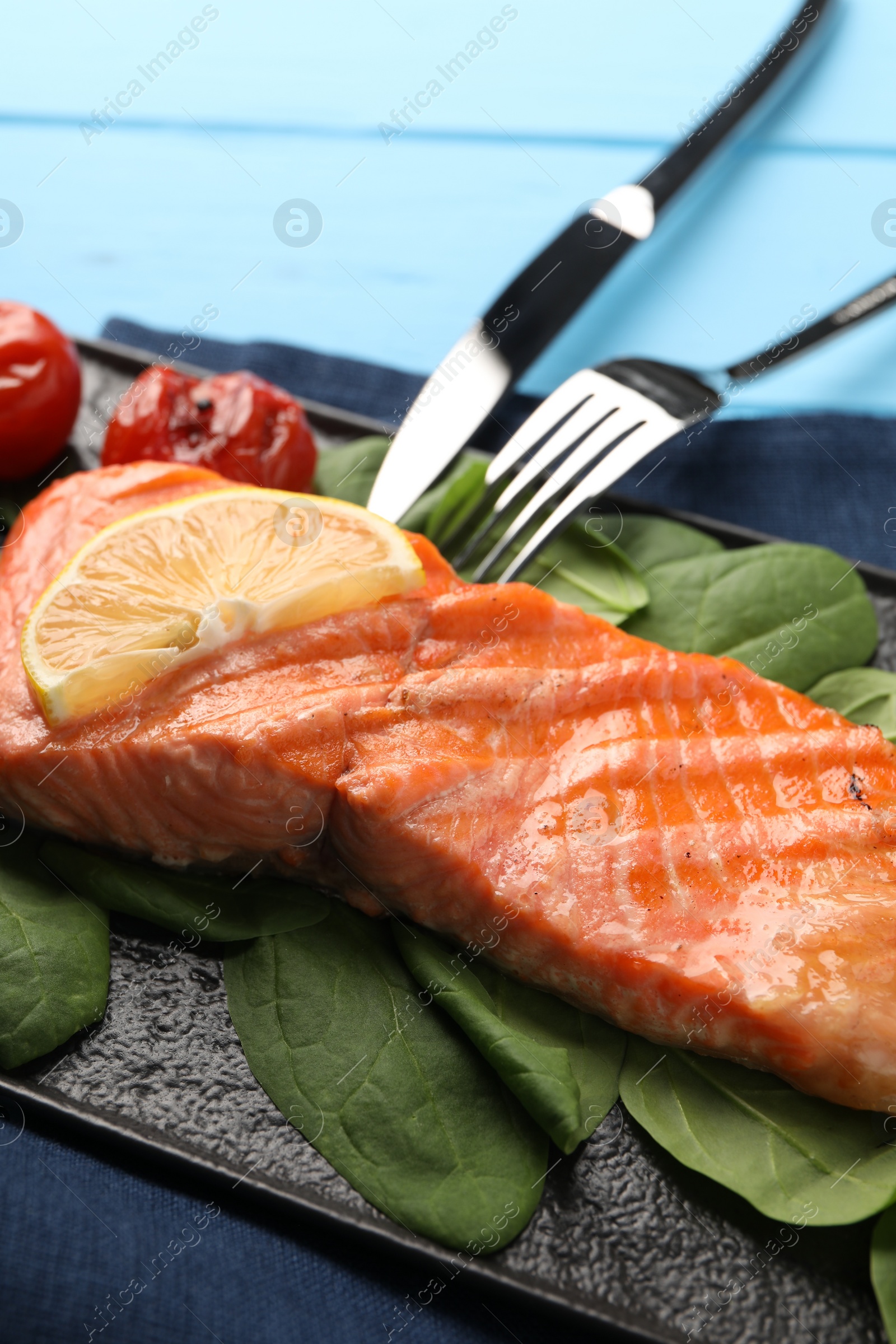 Photo of Tasty grilled salmon with spinach and lemon served on table, closeup