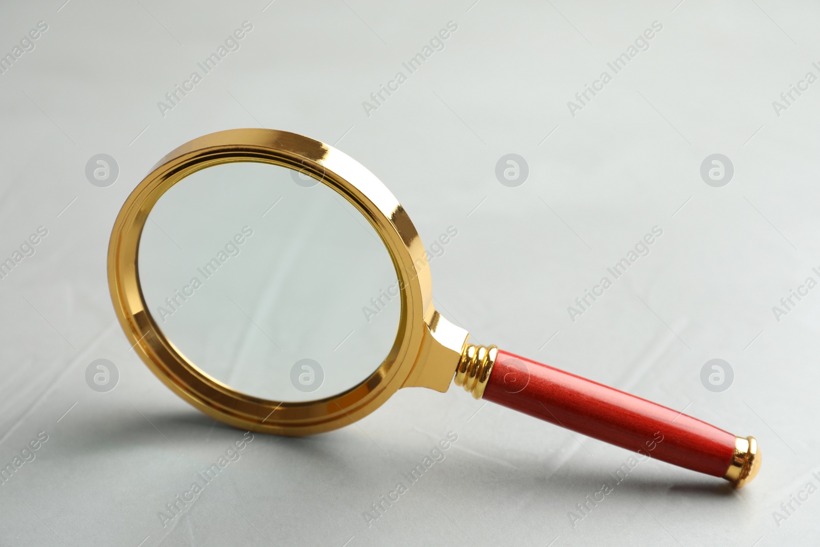 Photo of Magnifier glass on light grey stone background, closeup. Find keywords concept