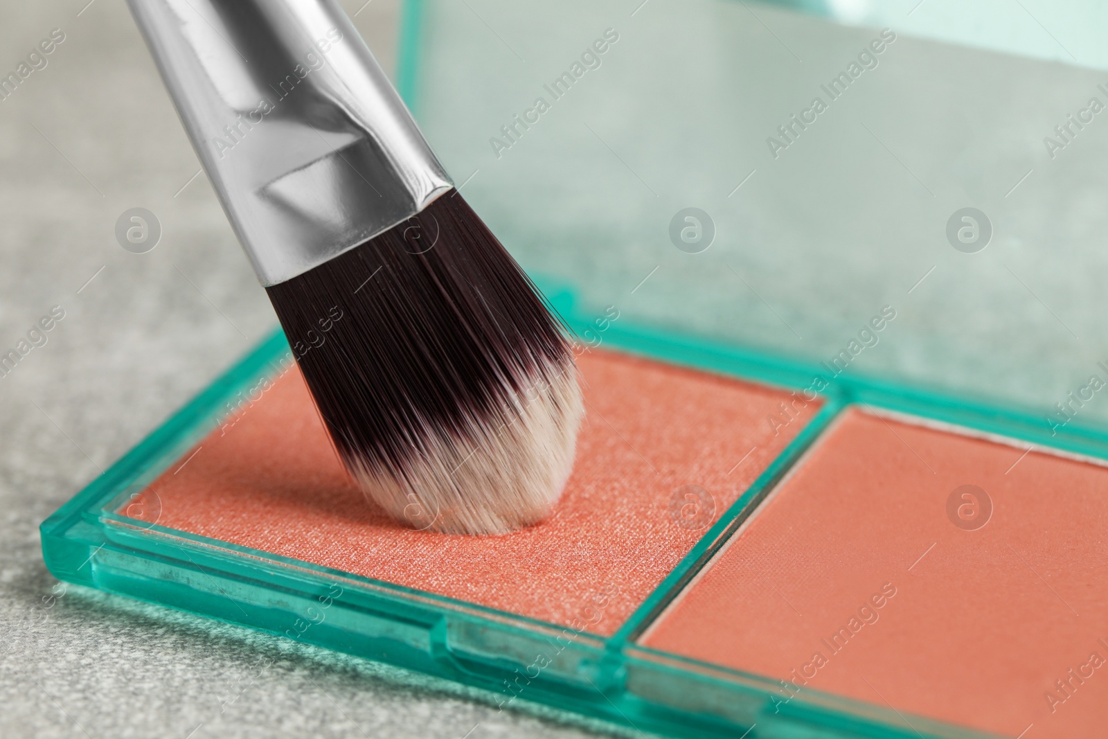 Photo of Mini blush palette with brush on grey table, closeup