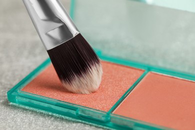 Mini blush palette with brush on grey table, closeup