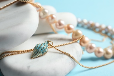 Photo of White marble stones with elegant jewelry on light blue background, closeup