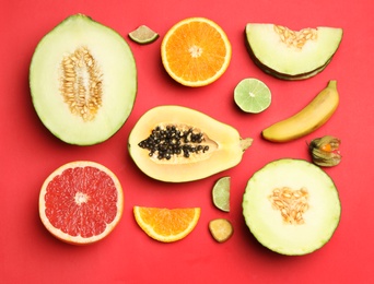 Photo of Flat lay composition with tasty melon and fresh tropical fruits on red background