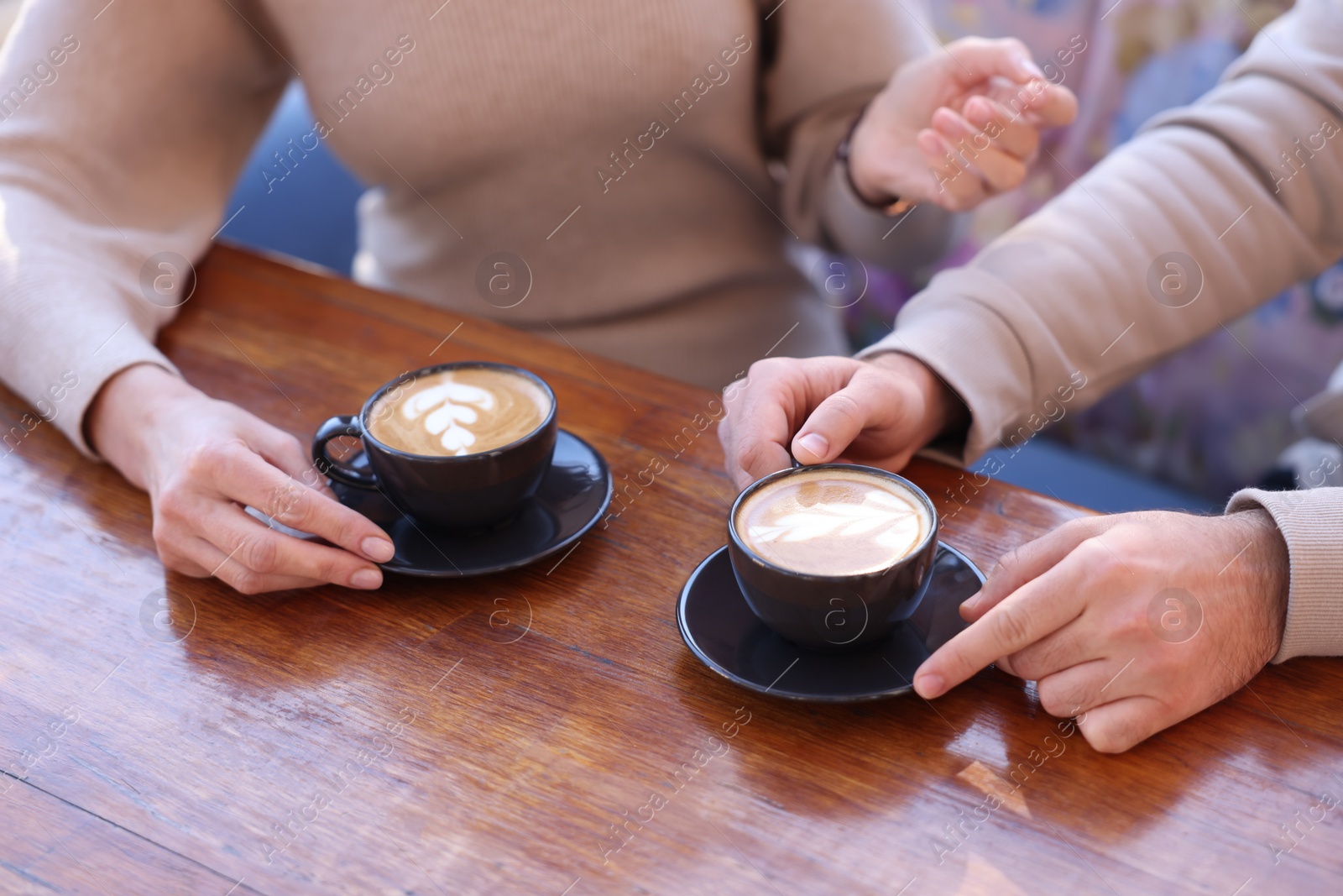 Photo of Couple with cups of aromatic coffee at wooden table, closeup