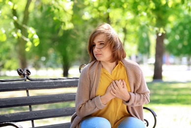 Photo of Mature woman having heart attack on bench in park