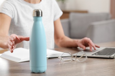 Woman taking thermo bottle indoors, closeup view