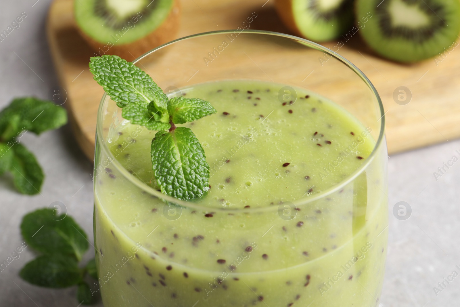 Photo of Delicious kiwi smoothie on light grey table, closeup