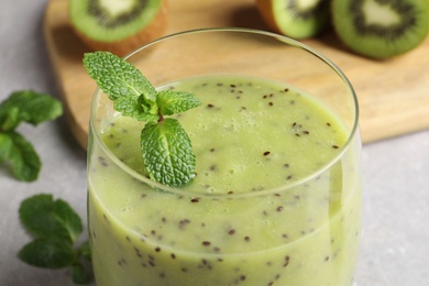 Photo of Delicious kiwi smoothie on light grey table, closeup