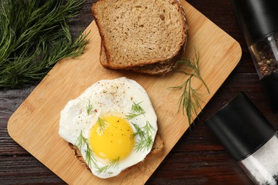 Photo of Tasty sandwich with fried egg on wooden table, flat lay