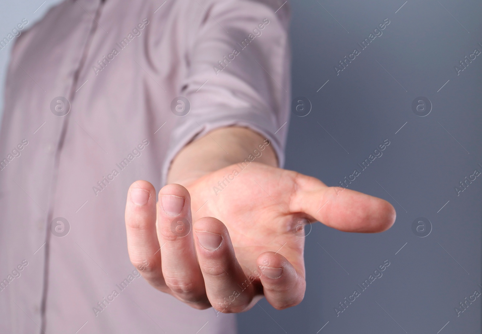 Photo of Man holding something in his hand on grey background, closeup