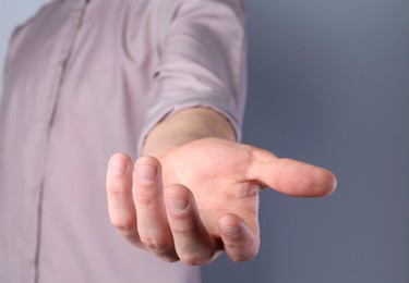 Photo of Man holding something in his hand on grey background, closeup
