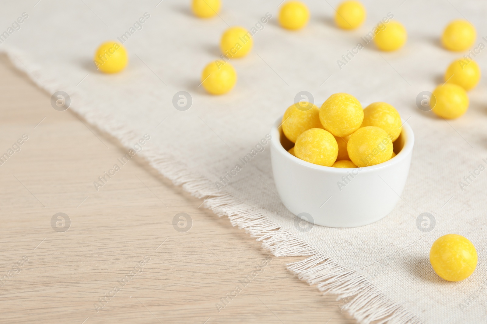 Photo of Tasty lemon drops on wooden table. Space for text