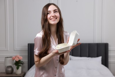 Beautiful young woman holding her Birthday cake in bedroom