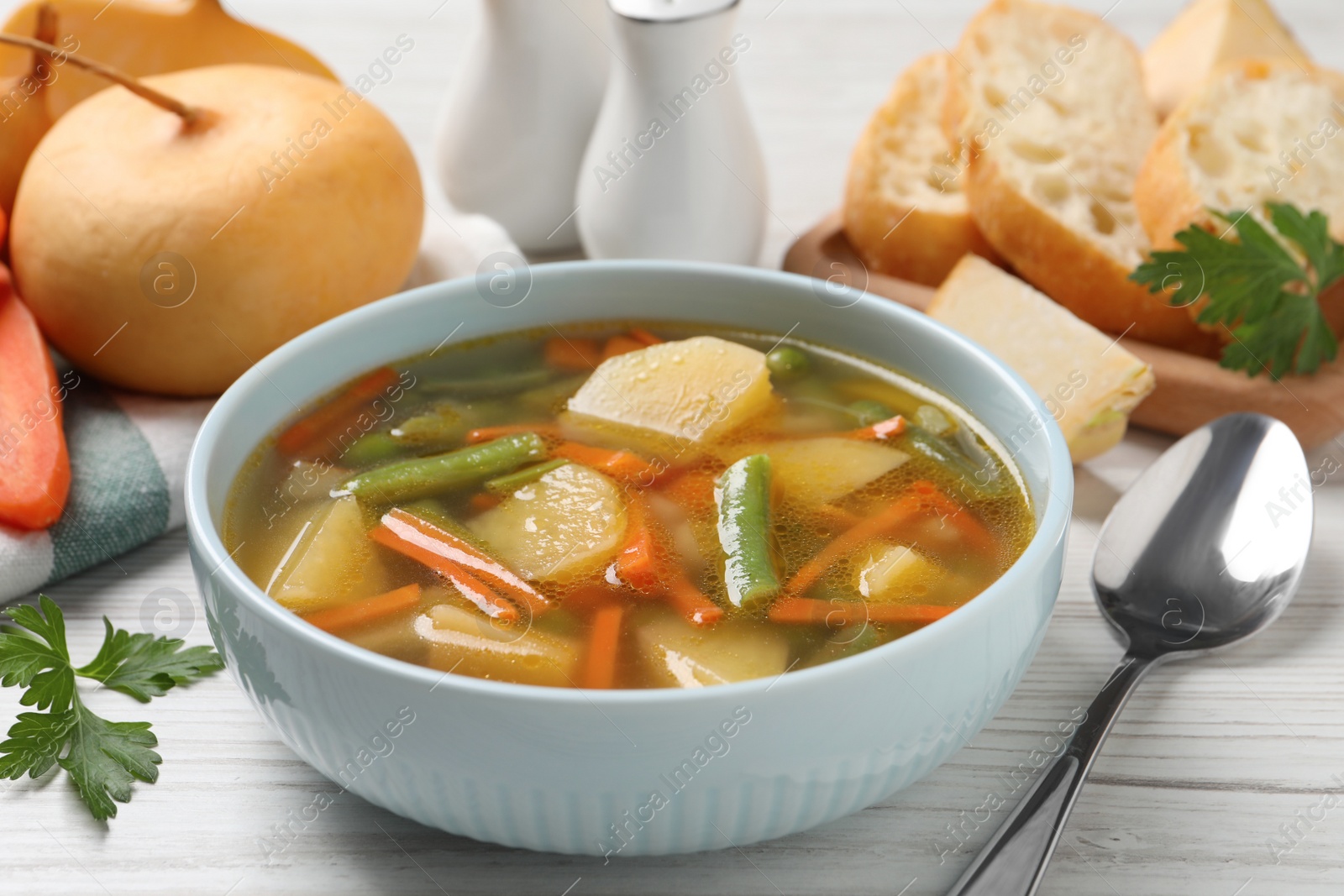 Photo of Bowl of tasty turnip soup and spoon on white wooden table, closeup