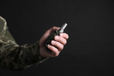 Photo of Soldier holding hand grenade on black background, closeup with space for text. Military service