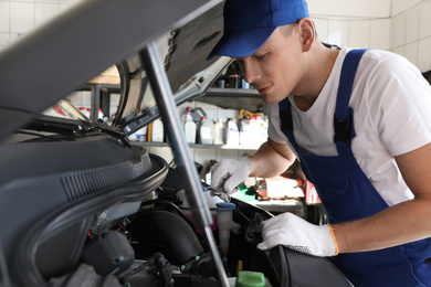 Professional auto mechanic fixing modern car in service center