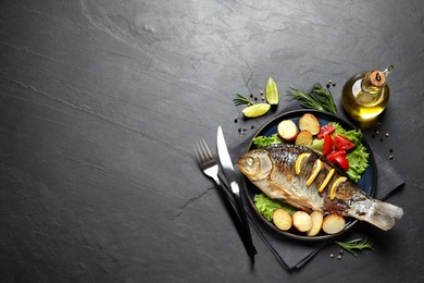 Photo of Tasty homemade roasted crucian carp served on black table, flat lay and space for text. River fish