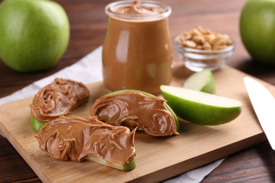 Slices of fresh green apple with peanut butter on wooden table, closeup