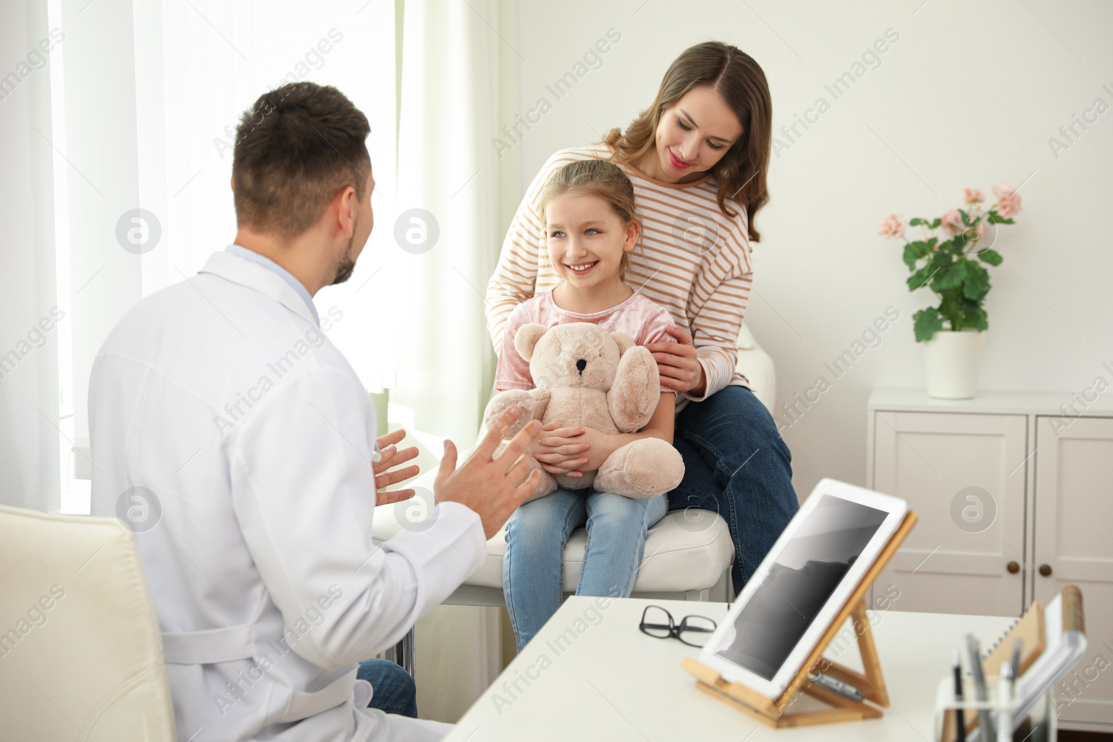 Photo of Mother and daughter visiting pediatrician. Doctor working with patient in hospital