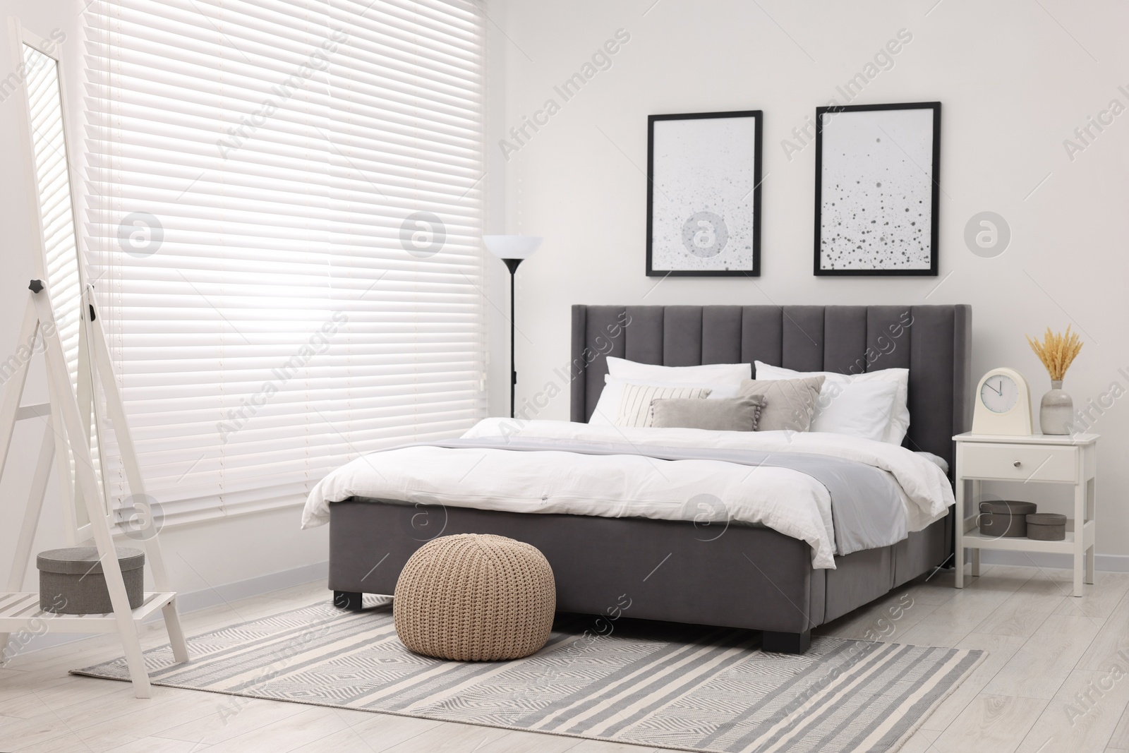 Photo of Stylish bedroom interior with large bed, mirror and lamp