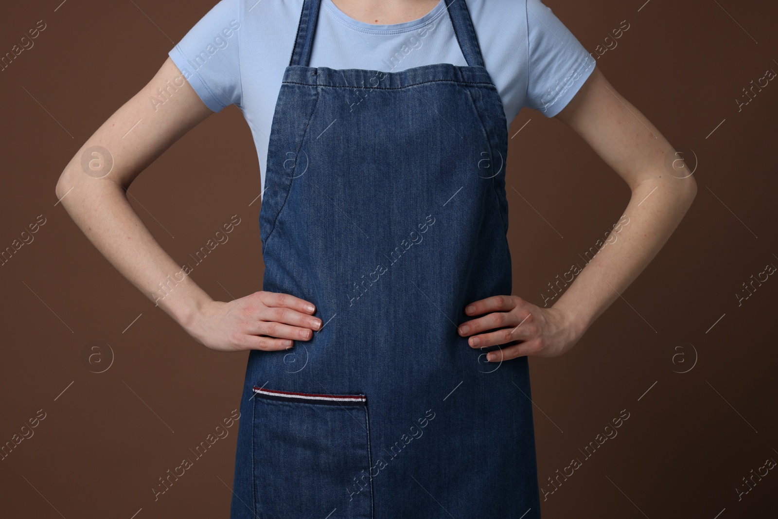 Photo of Woman wearing kitchen apron on brown background, closeup. Mockup for design