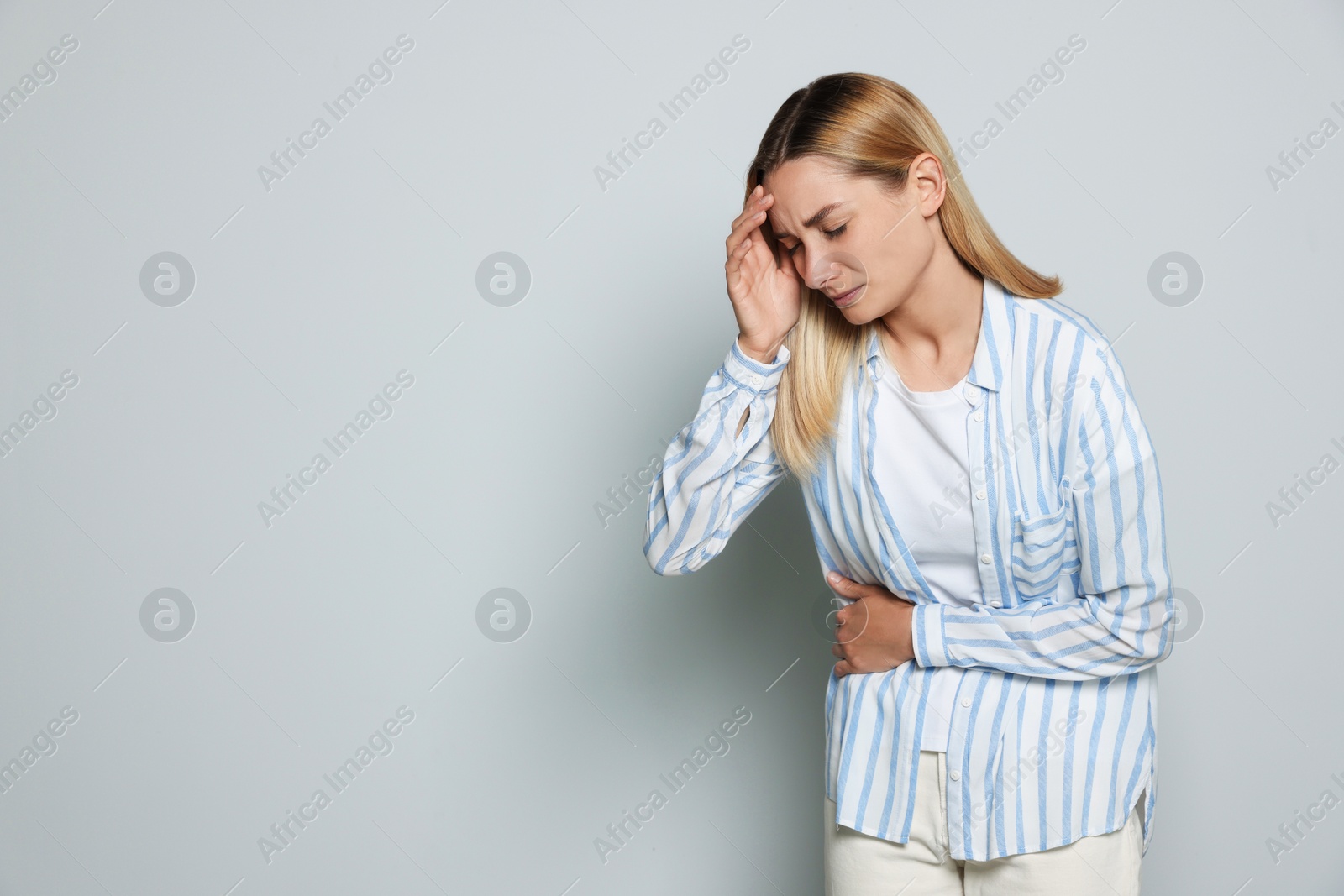 Photo of Young woman suffering from menstrual pain on light grey background, space for text