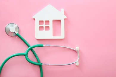 Flat lay composition with house model and stethoscope on color background, top view