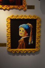 Photo of AMSTERDAM, NETHERLANDS - JULY 16, 2022: Girl with a Pearl Earring by Johannes Vermeer made of colorful Lego constructor on white wall indoors