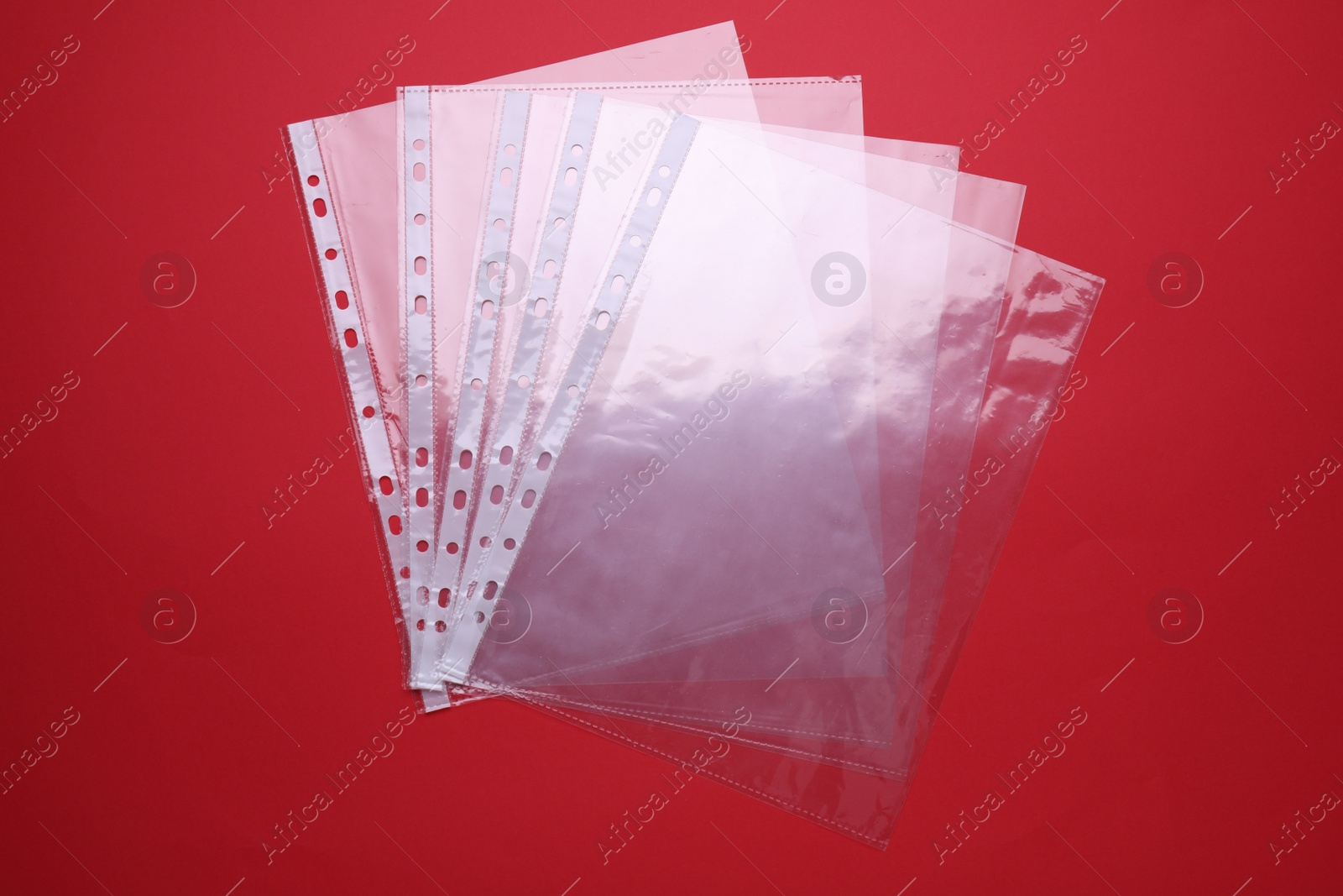 Photo of Empty punched pockets on red background, flat lay