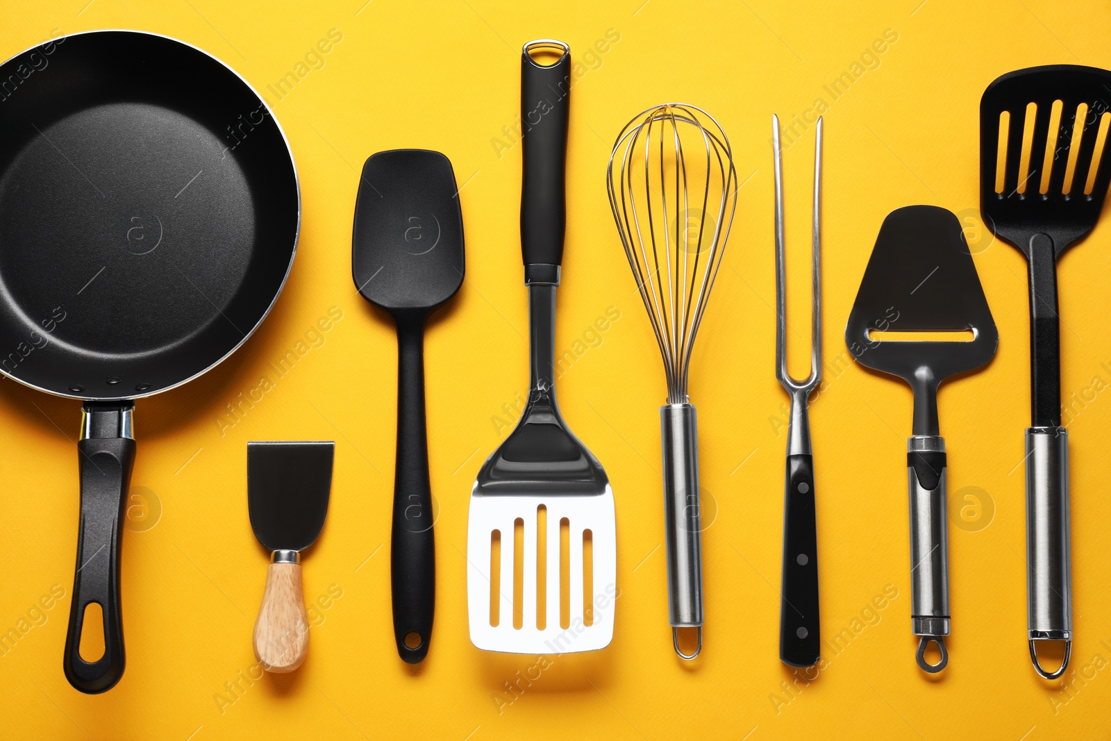 Photo of Different spatulas and other kitchen utensils on orange background, flat lay