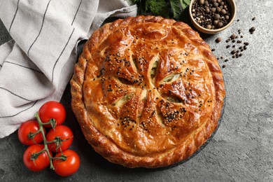 Photo of Tasty homemade pie, spices and fresh tomatoes on grey table, flat lay