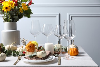 Beautiful autumn table setting with bouquet indoors. Plates, cutlery, glasses and floral decor