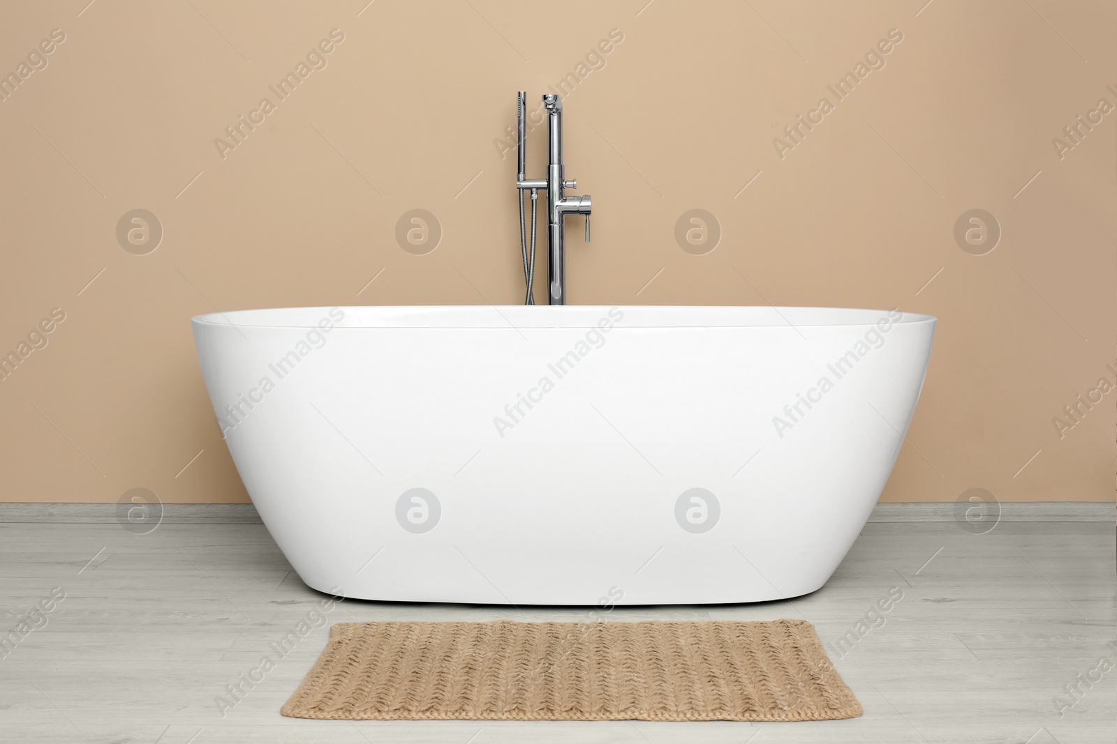 Photo of Beautiful white tub near beige wall in bathroom. Interior design