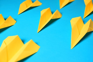 Photo of Many yellow paper planes on light blue background, closeup