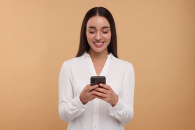 Photo of Happy young woman using smartphone on beige background