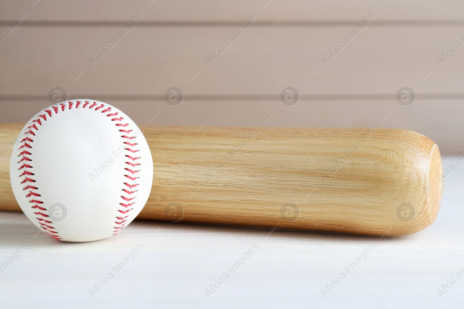 Photo of Baseball bat and ball on white wooden table. Sports equipment