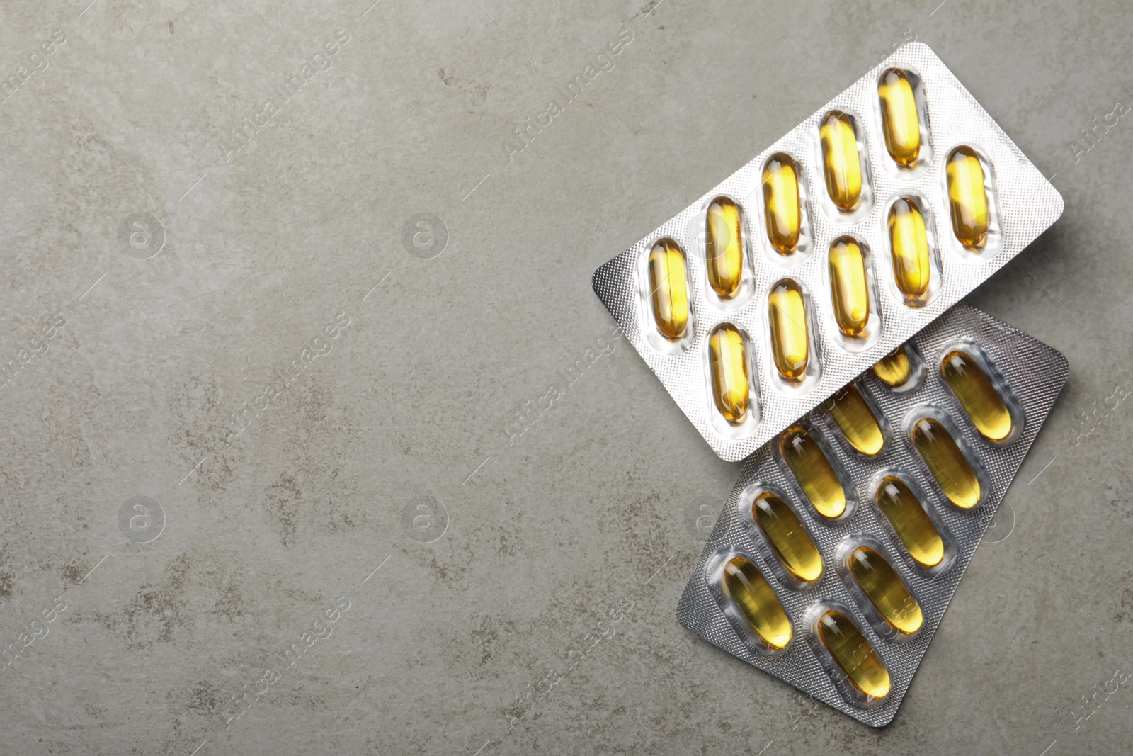 Photo of Dietary supplement capsules in blister packs on grey table, flat lay. Space for text