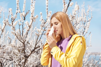 Woman suffering from seasonal allergy outdoors, space for text