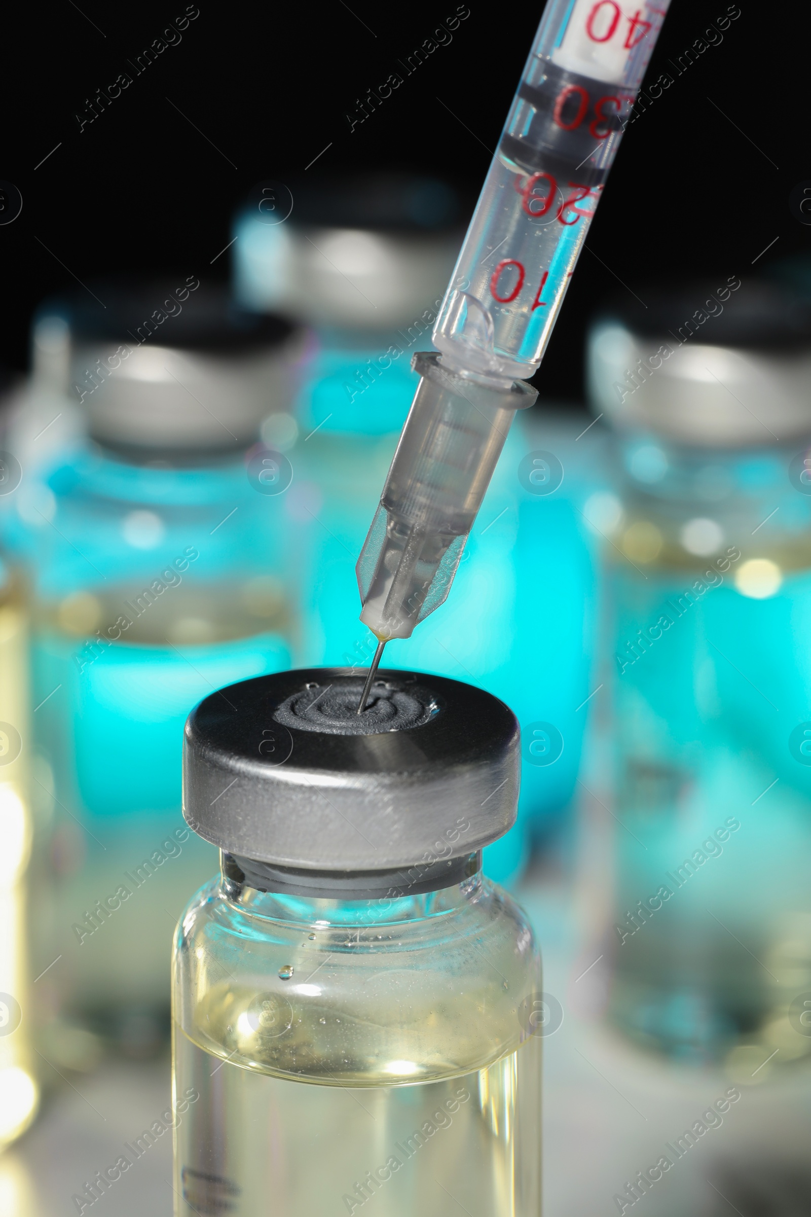 Photo of Filling syringe with medicine from vial against blurred background, closeup