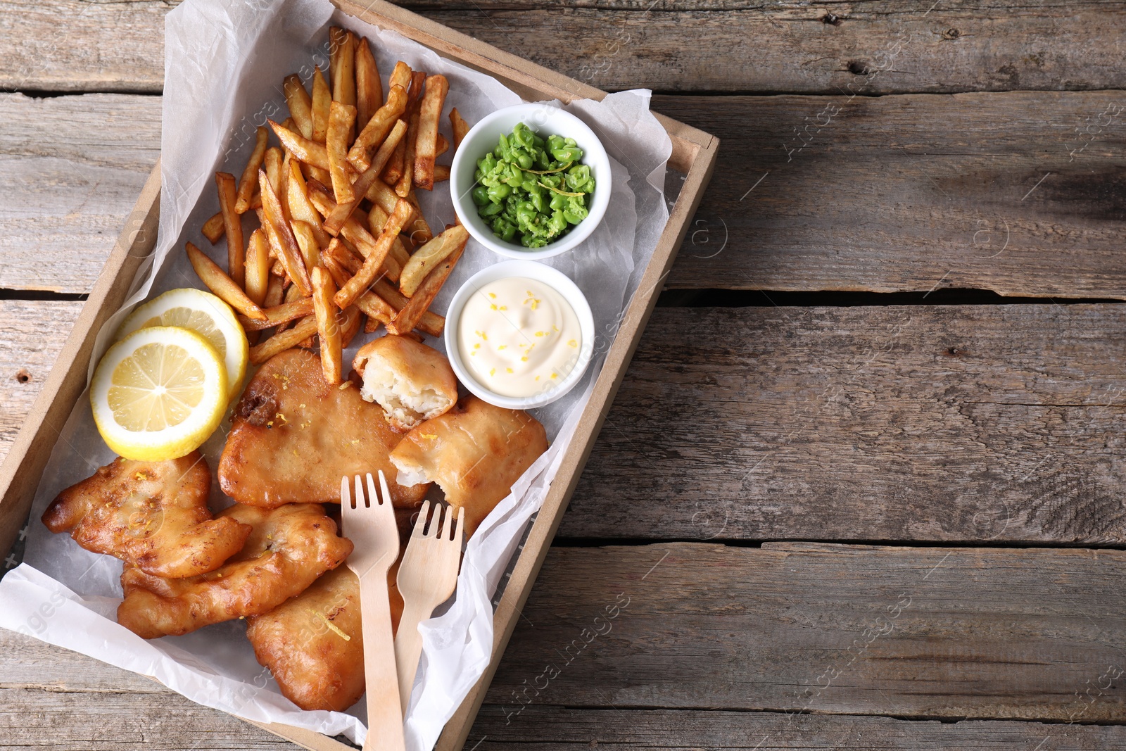 Photo of Tasty fish, chips, sauce and peas on wooden table, top view. Space for text