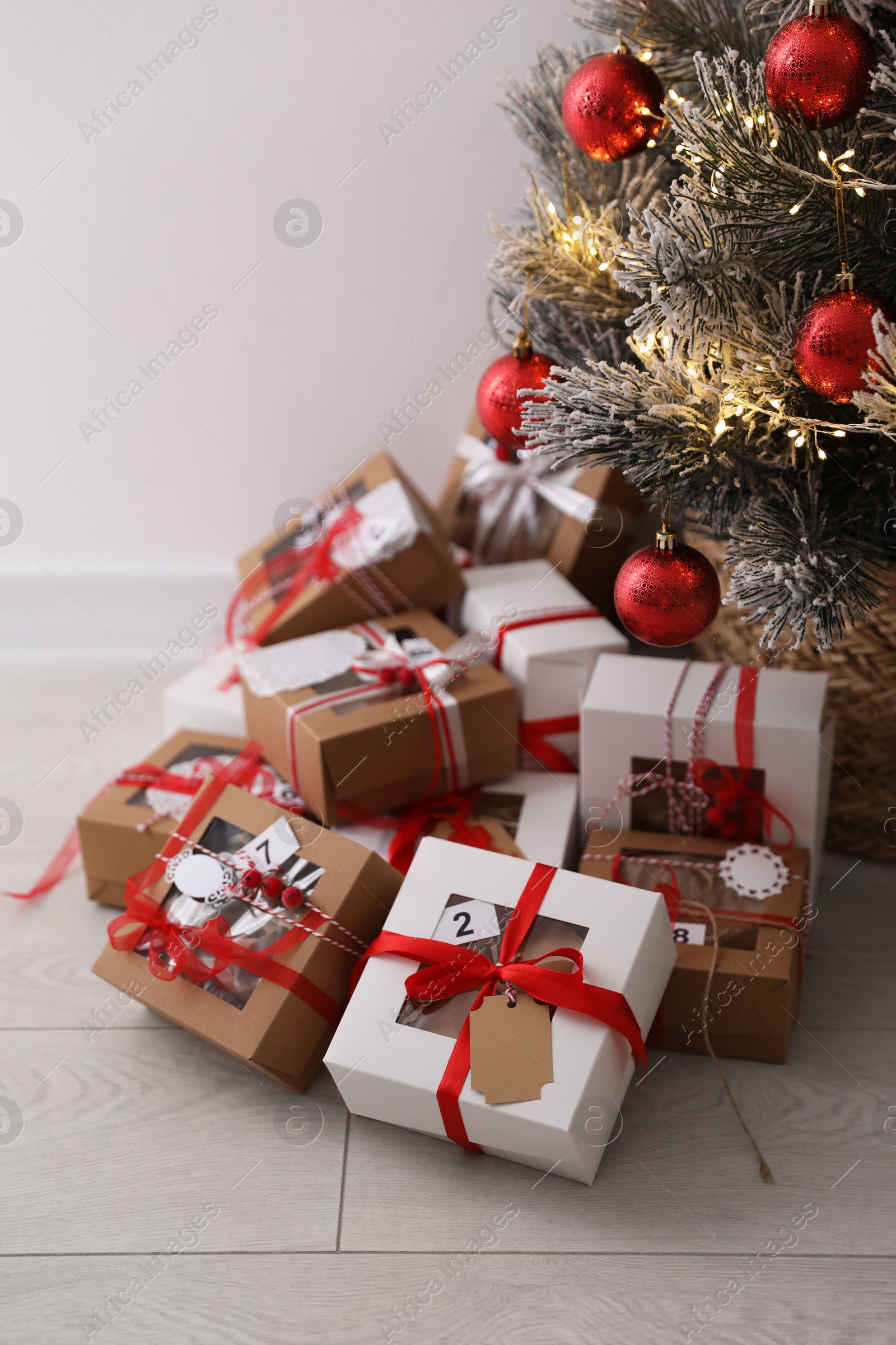 Photo of Pile of gift boxes near beautiful Christmas tree on floor. Advent calendar