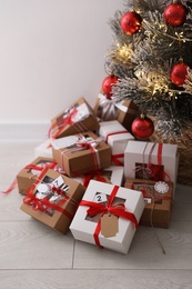 Photo of Pile of gift boxes near beautiful Christmas tree on floor. Advent calendar