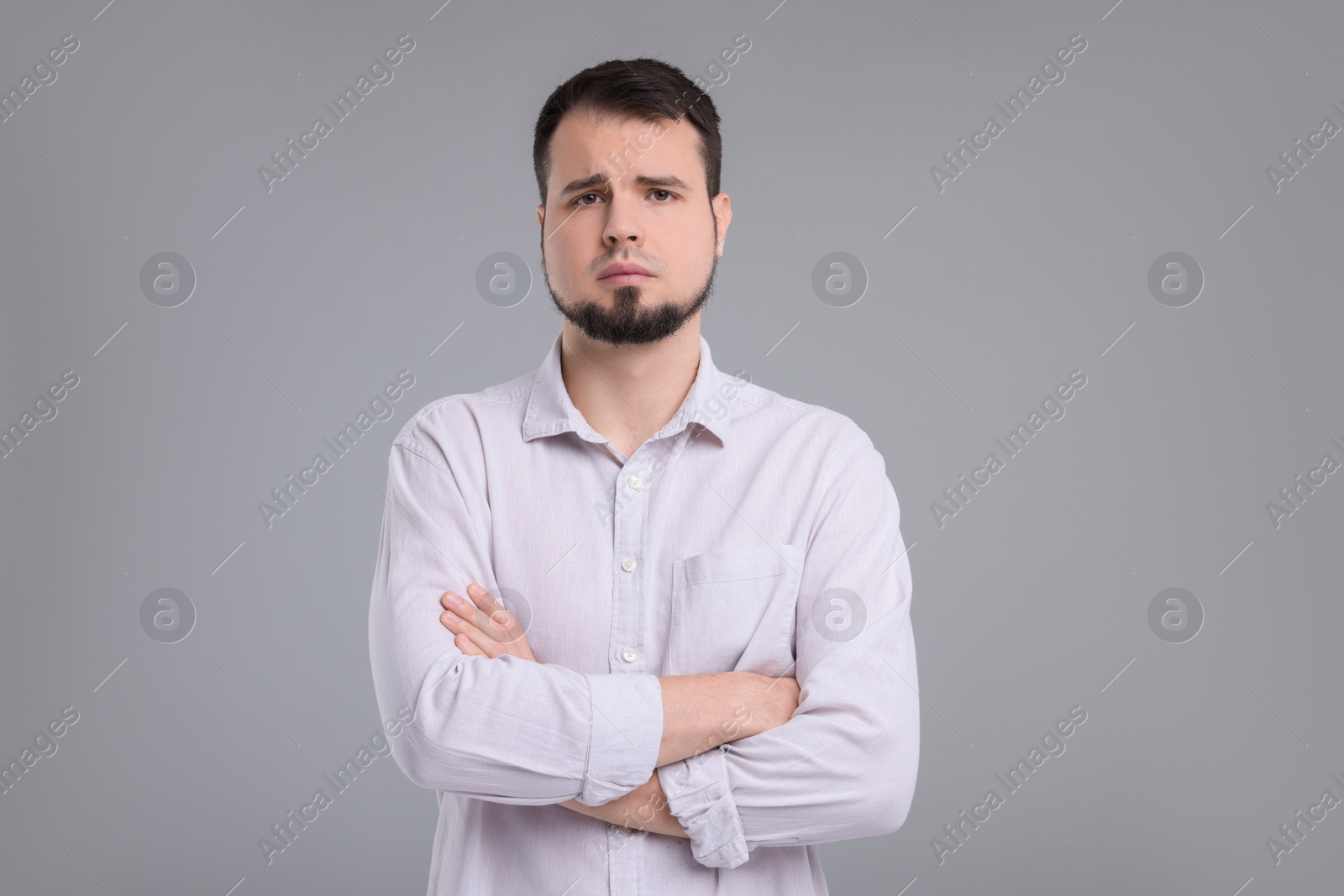 Photo of Portrait of sad man with crossed arms on grey background