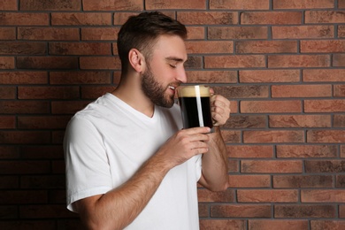 Handsome man with cold kvass near brick wall. Traditional Russian summer drink