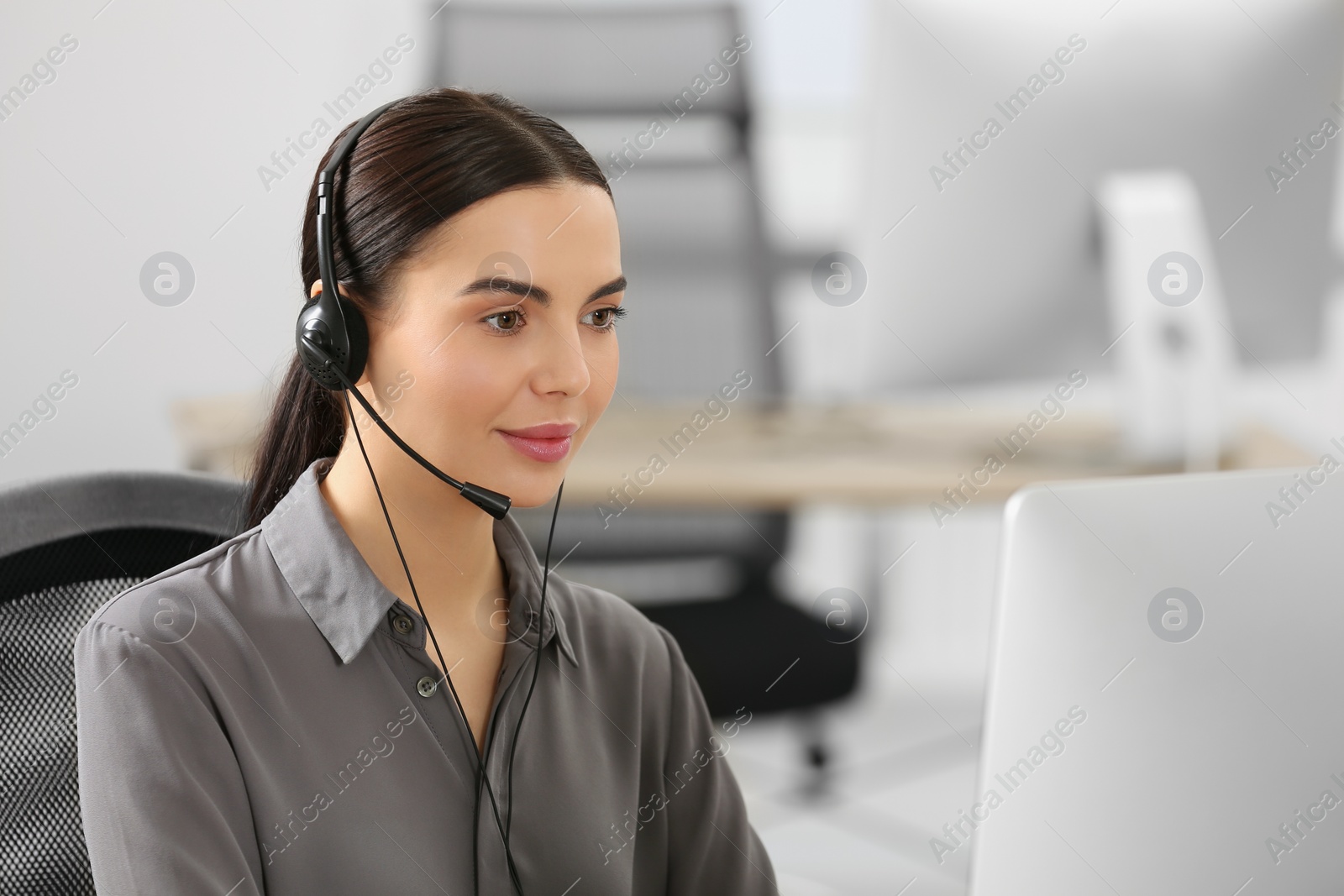 Photo of Hotline operator with headset working on computer in office